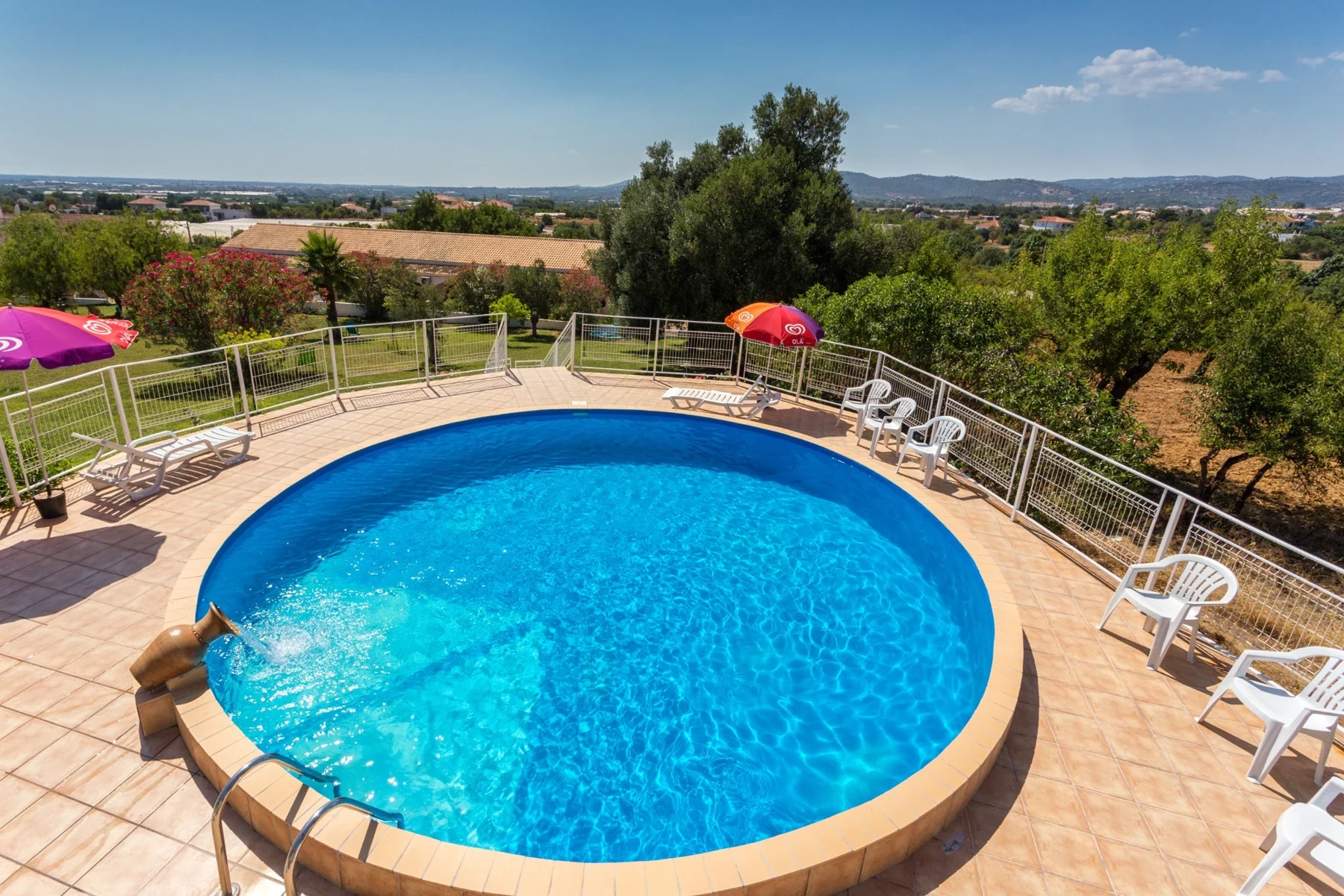 Piscine ronde entourée de transats avec vue sur le jardin