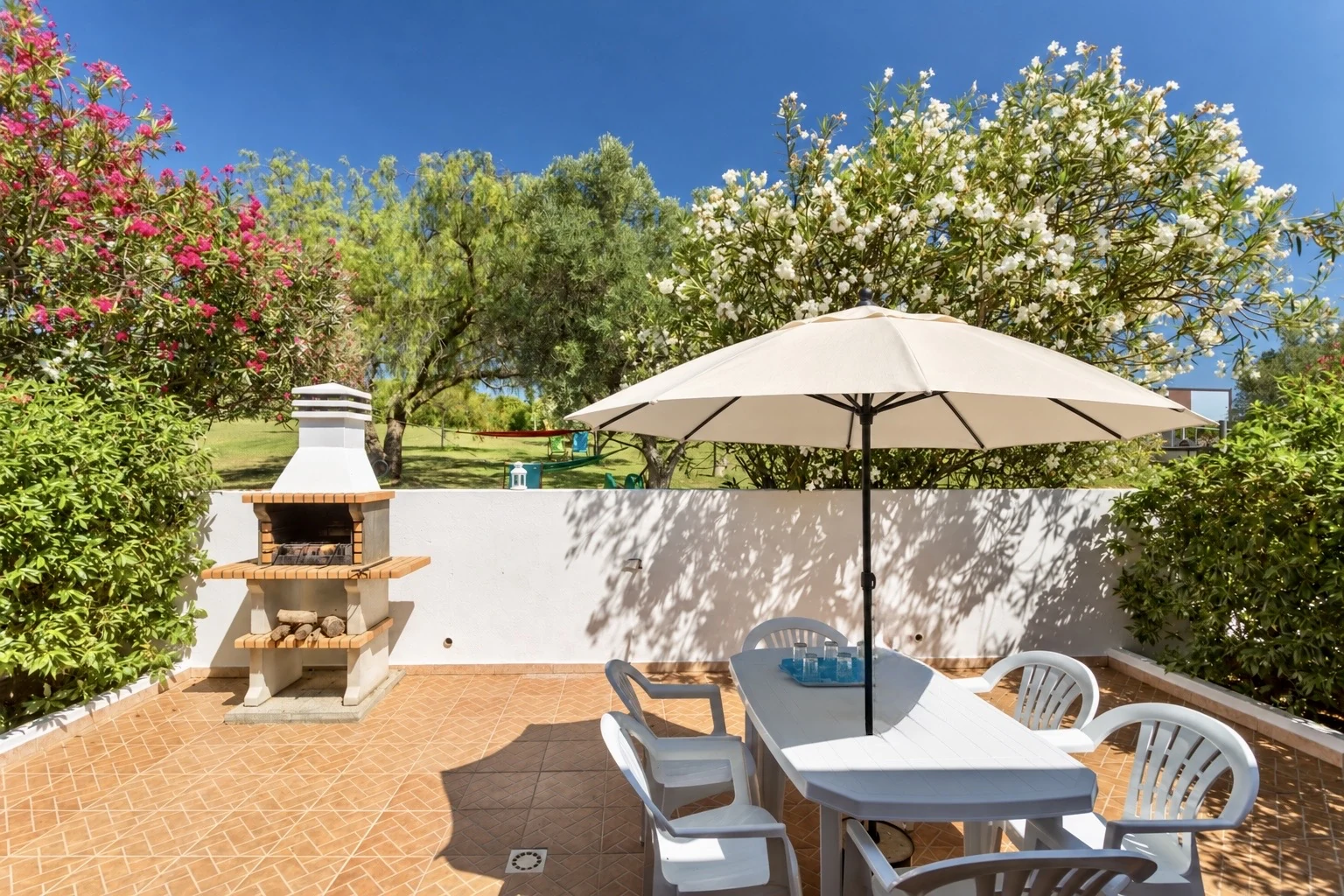 Terrasse privative avec table, parasol et barbecue